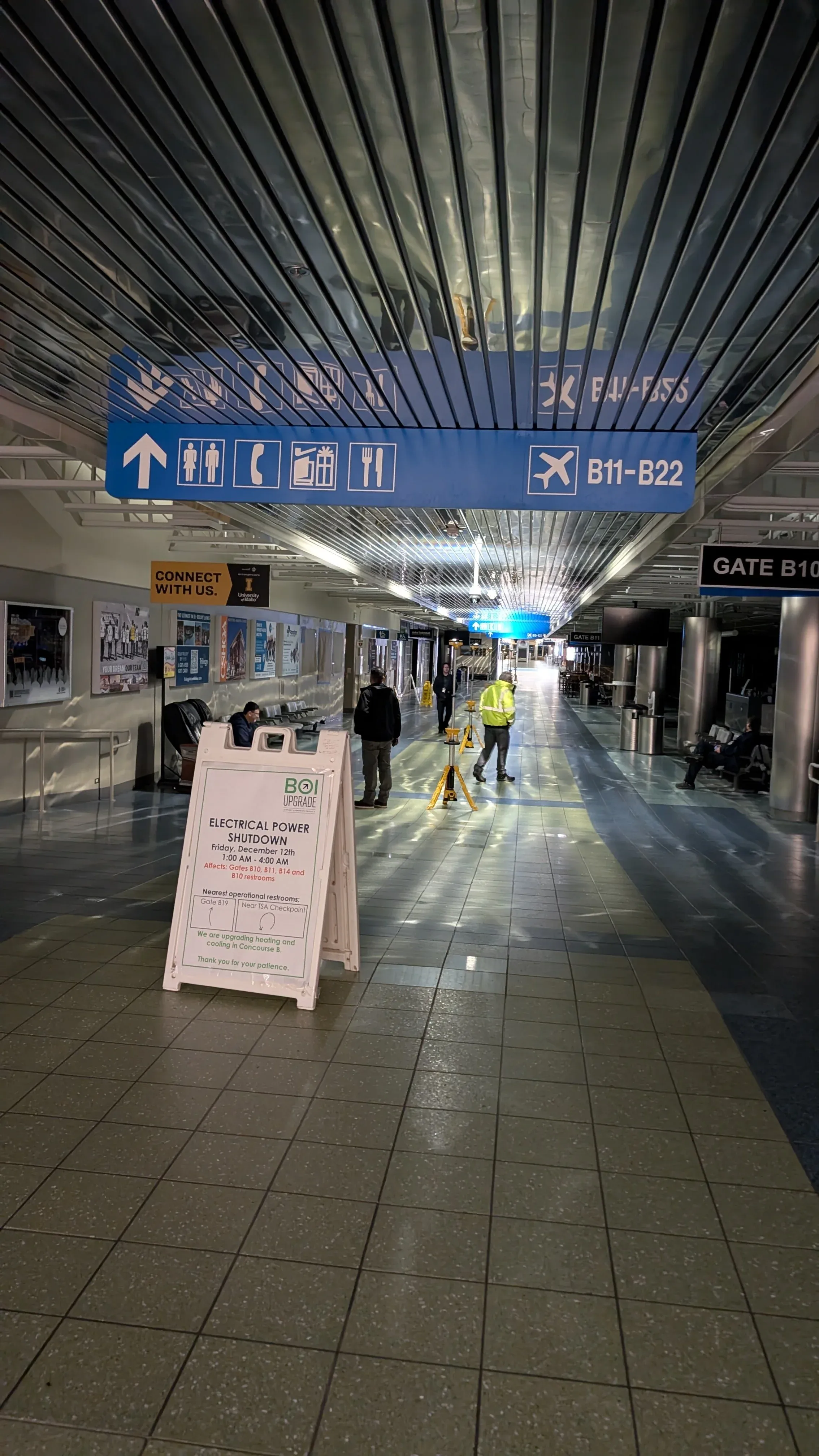 A quiet concourse corridor with overhead wayfinding signage.