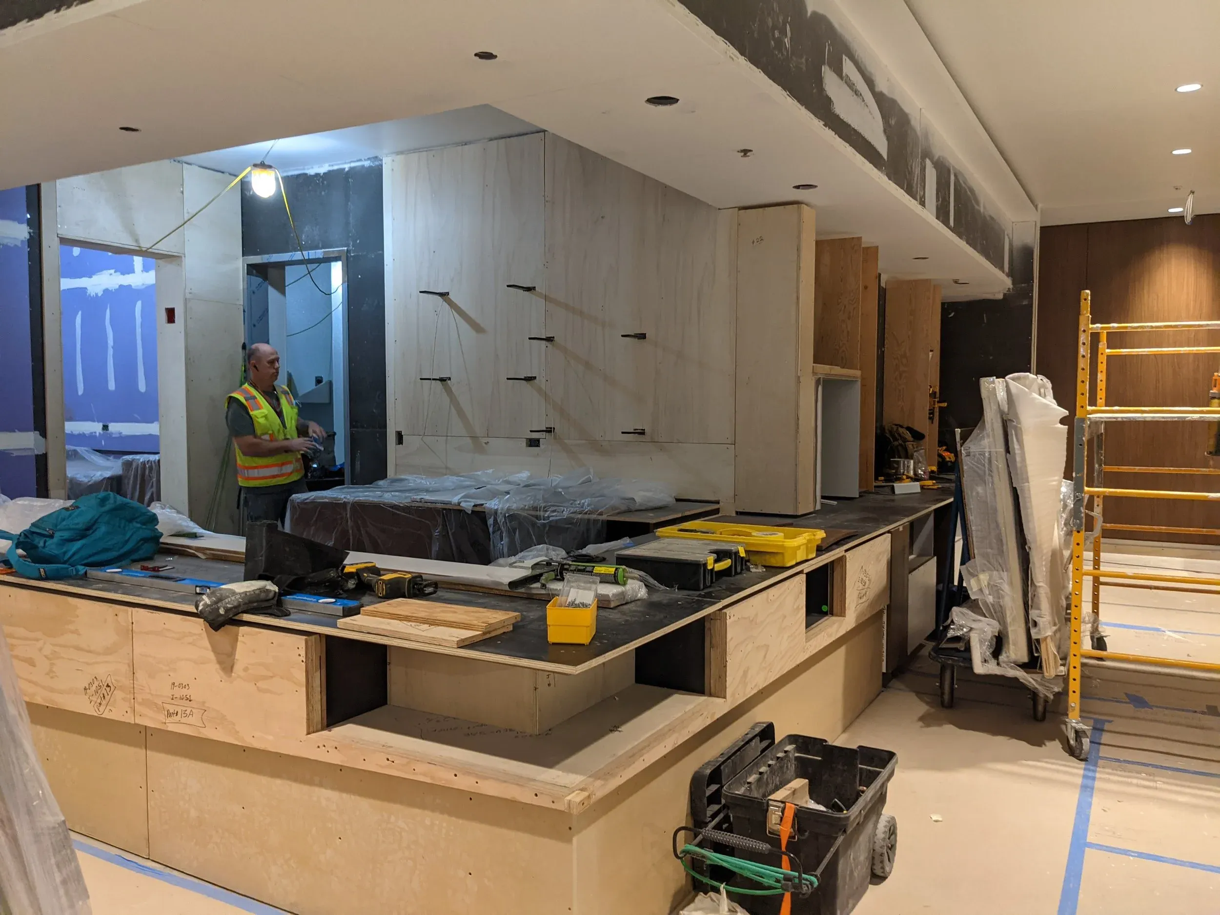 Millwork being set in the A43 club at Detroit, a worker in a safety vest at the counter.