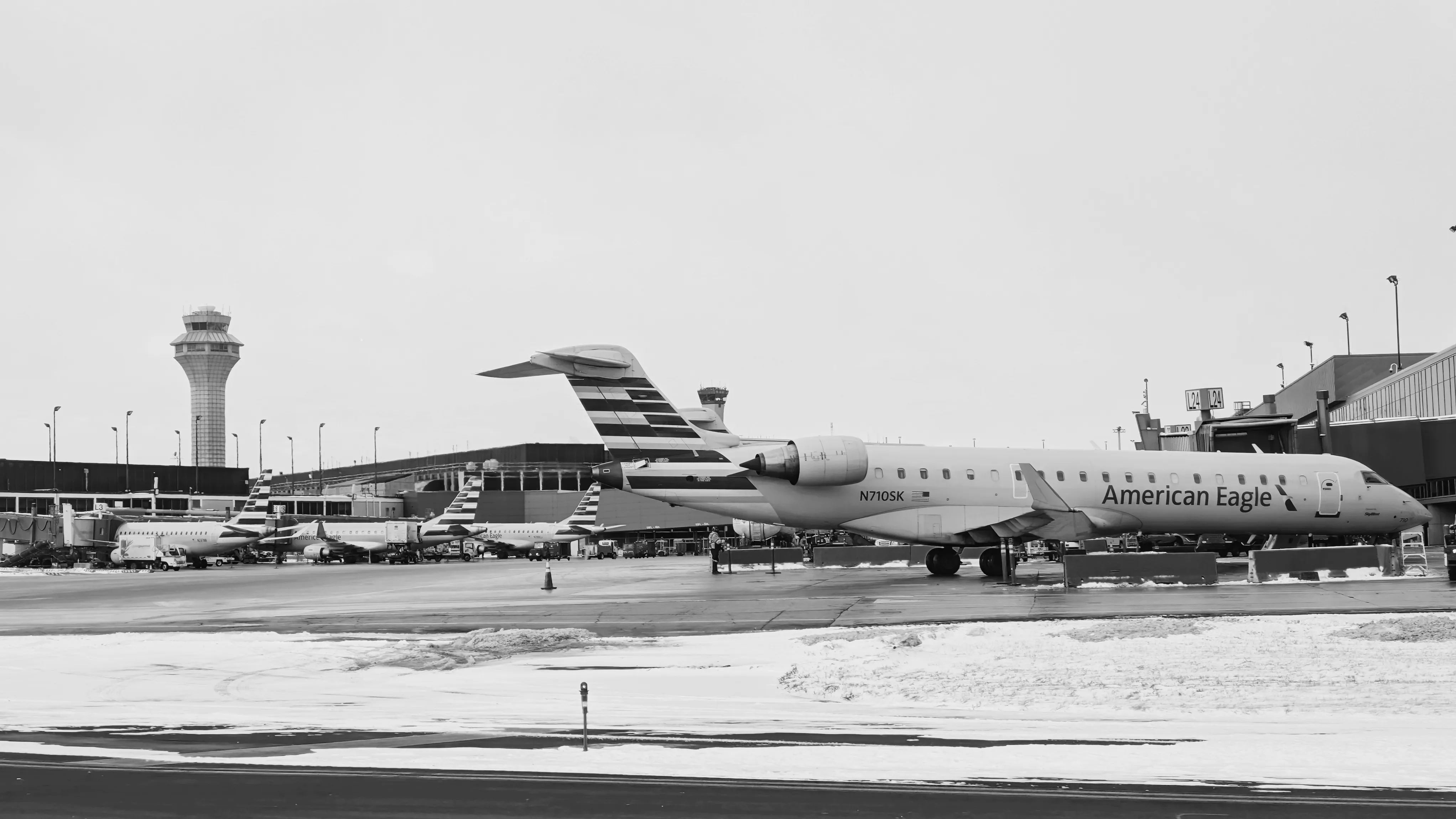 An American Eagle regional jet at the Terminal 3 L-gates at O'Hare, snow on the ramp.