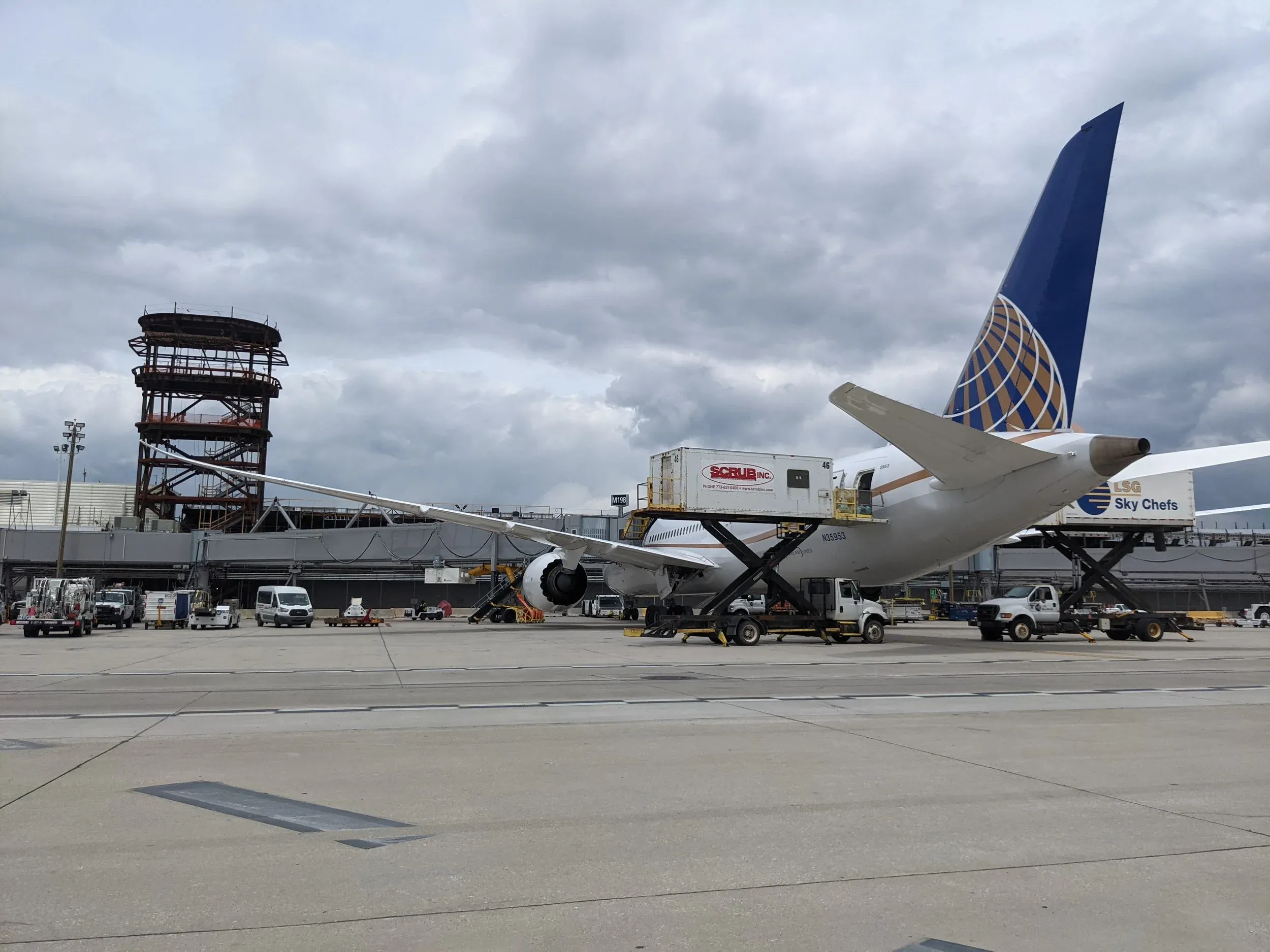 An aircraft at an O’Hare Terminal 5 gate with a construction tower crane working behind it.