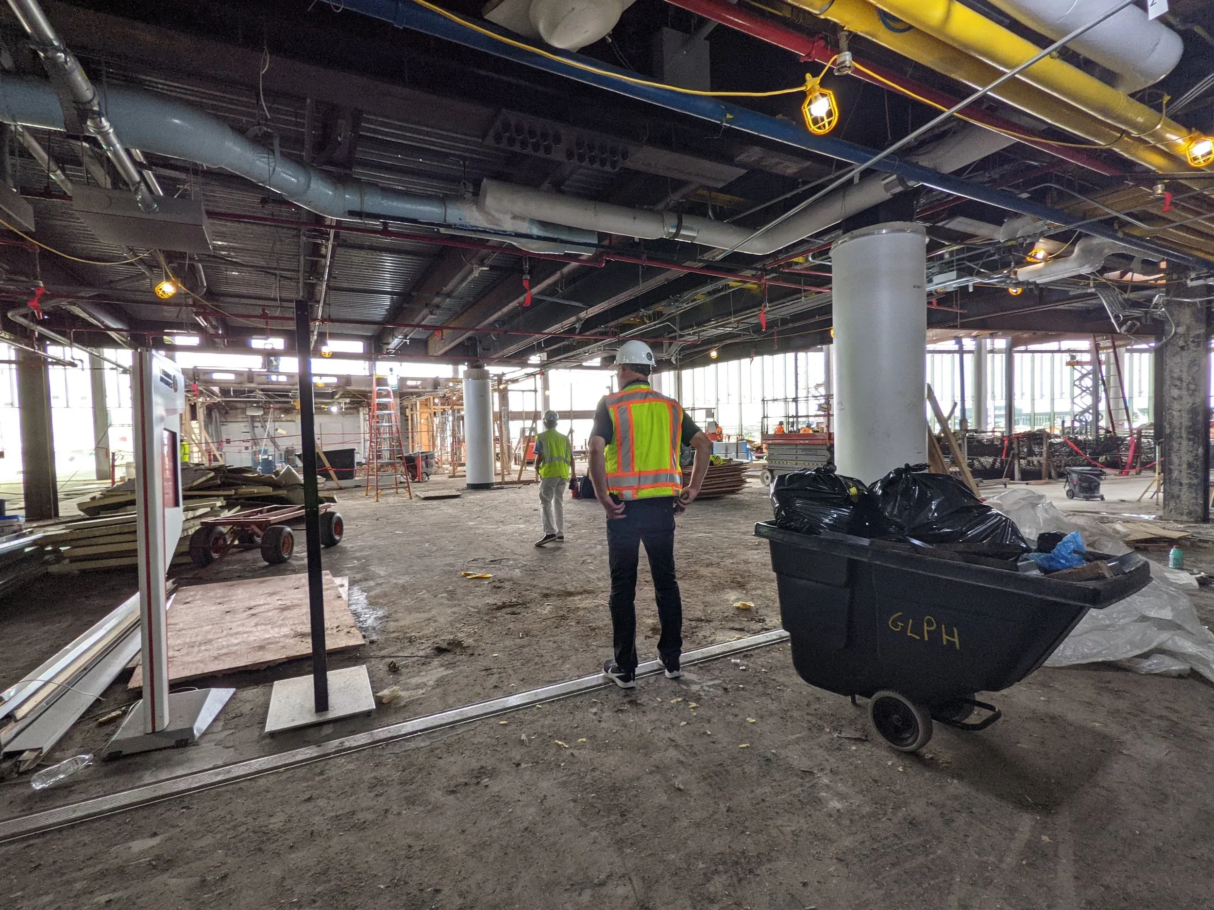 A gutted interior at O’Hare Terminal 5, crews working among bare columns and overhead services.