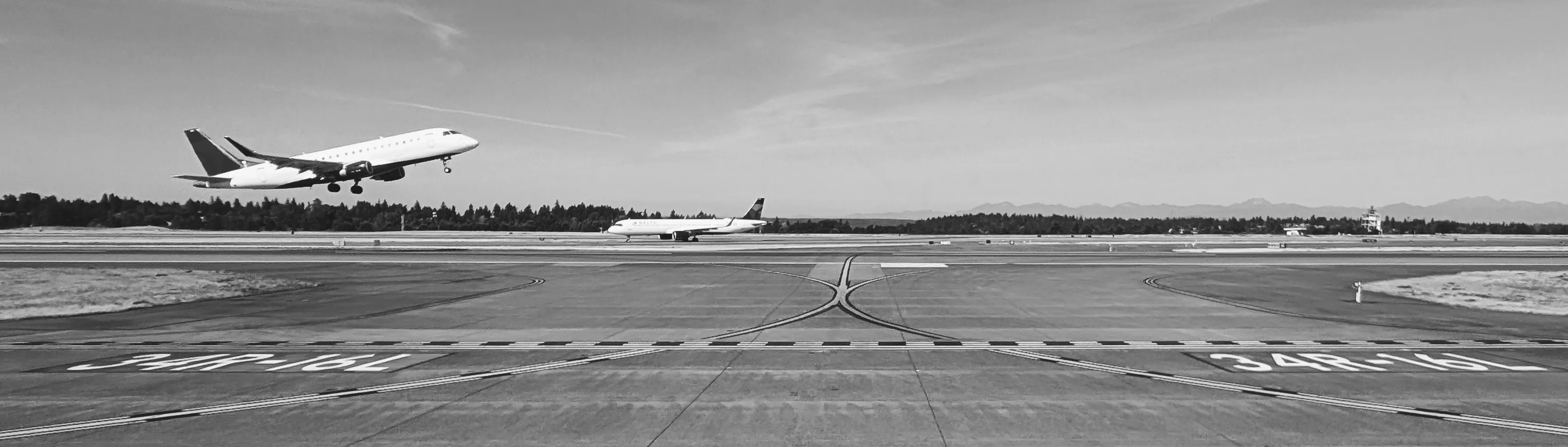 An Embraer E175 climbing away from Seattle-Tacoma at dusk.